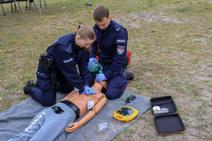 Umundurowani policjanci biorący udział w pozorowanej sytuacji kwalifikowanej pierwszej pomocy osobie wyciągniętej z wody po podtopieniu.