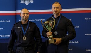 Umundurowani policjanci z pucharem w ręku.