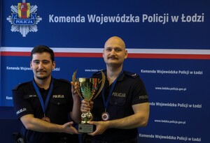 Umundurowani policjanci z pucharem w ręku.