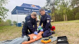Umundurowani policjanci biorący udział w pozorowanej sytuacji kwalifikowanej pierwszej pomocy osobie wyciągniętej z wody po podtopieniu.