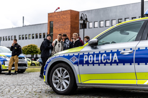 Policyjny oznakowany radiowóz obok młodzież biorąca udział w targach