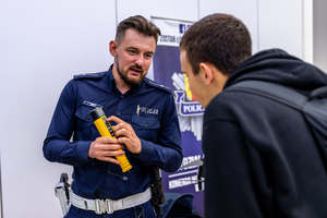Umundurowany policjant prezentującym urządzenie AlcoBlow