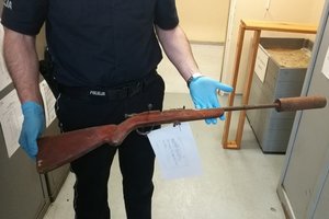 policjant zabezpiecza znalezioną broń