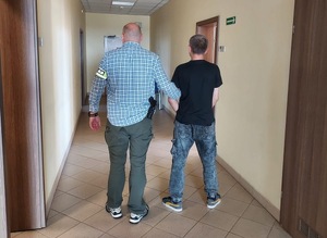 Policjant trzyma zatrzymanego.