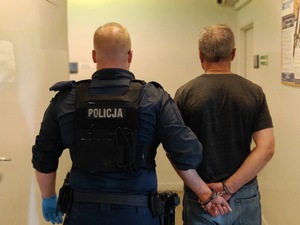 Policjant trzyma zatrzymanego.