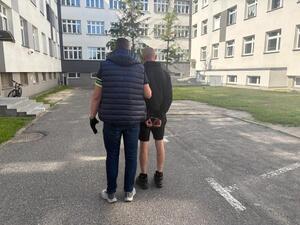 Policjant trzyma zatrzymanego.