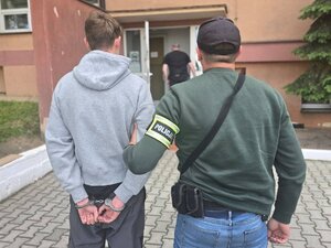Policjant trzyma zatrzymanego.