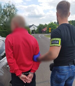 Policjant trzyma zatrzymanego.