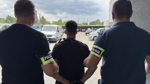 Policjant trzyma zatrzymanego.