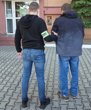 Policjant trzyma zatrzymanego.