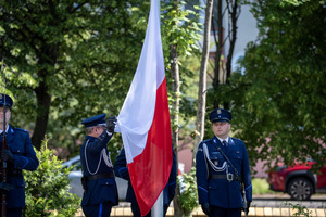 Funkcjonariusze Policji trzymający w ręku flagę Polski.