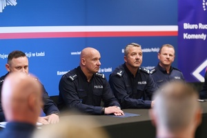 Umundurowani funkcjonariusze zasiadający za stołem.