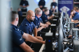 Umundurowani policjanci przed komputerami rozwiązujący test.