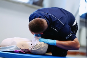 Policjant umundurowany udzielający pierwszej pomocy podczas konkursu.