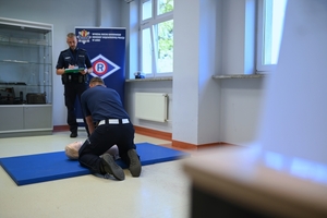 Policjant umundurowany udzielający pierwszej pomocy podczas konkursu.