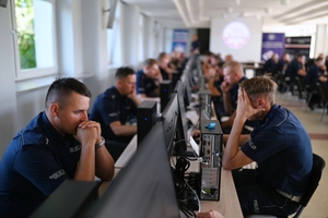 Umundurowani policjanci przed komputerami rozwiązujący test.