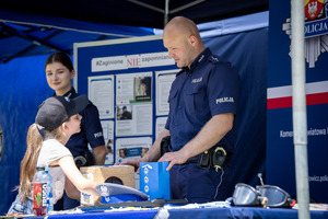 Stoiska promocyjne, policjanci i dzieci pod namiotami.