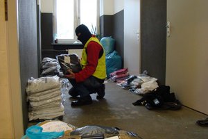 Policjant prowadzi oględziny zabezpieczonych ubrań