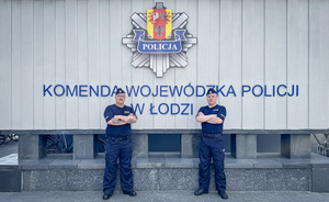 Policjanci stoją na tle napisu Komenda Wojewódzka Policji w Łodzi.