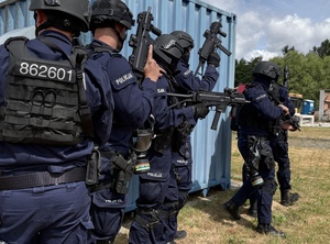 Umundurowani funkcjonariusze policji z bronią w ręku.
