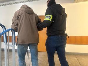 Policjant prowadzi zatrzymanego.