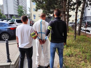 Nieumundurowani policjanci stoją z zatrzymanym mężczyzną.