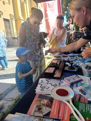 Policjantka pokazuje gadżetu dziecku na stoisku promocyjnym.