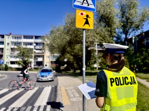 Policjantka trzyma notatnik, stoi przy przejściu dla pieszych.