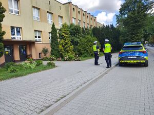 Policjanci i radiowóz w okolicy szkoły, lustracja oznakowania.