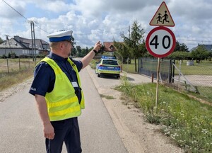 Policjant w okolicy szkoły sprawdza oznakowanie.