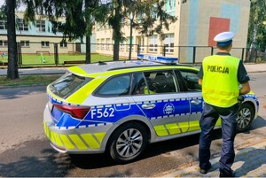 Policjant stoi przy samochodzie.