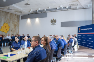 Policjanci siedzą za stołami.