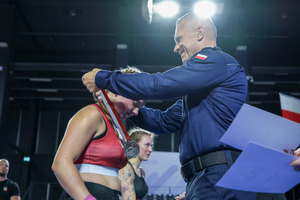 Nadinspektor Arkadiusz Sylwestrzak wręcza medal zawodniczce.