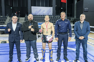 Zawodnik z medalem w towarzystwie Komendanta Wojewódzkiego Policji w Łodzi i jeszcze 3 mężczyzn.