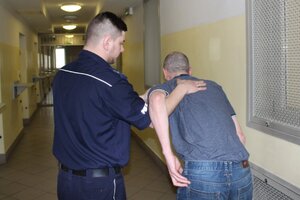policjant prowadzi zatrzymanego