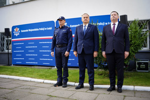 Umundurowany policjant stoi z dwoma mężczyznami.
