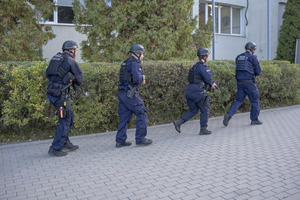 Czterech umundurowanych policjantów z hełmami na głowach i z bronią w rękach.