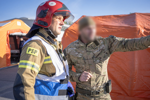 Policjant Samodzielnego Pododdziału Kontrterrorystycznego Policji stoi obok strażaka.