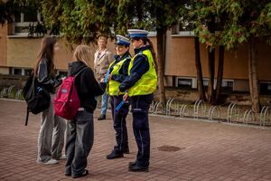Dwie policjantki rozdają odblaski dzieciom.