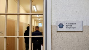Funkcjonariusz policji z osoba zatrzymaną w pomieszczeniu dla osób zatrzymanych.