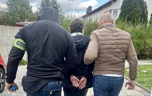 Funkcjonariusz policji z osobą poszukiwaną.