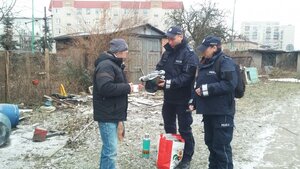 Policjanci przekazują bezdomnemu ciepłe koce.