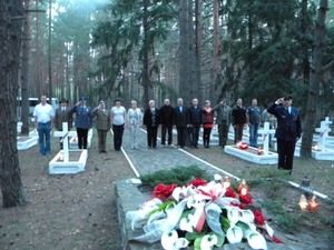 Zdjęcie uczestników spotkania stojących w szeregu przy grobach