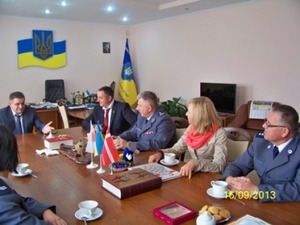 Zdjęcie dorosłych uczestników przedsięwzięcia w trakcie oficjalnego spotkania w sali udekorowanej flagami ukraińskimi