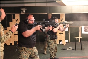 Zdjęcie czterech uczestników ćwiczeń w ochraniaczach słuchu w trakcie strzelania z broni długiej na strzelnicy