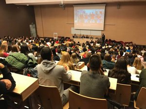 Aula studencka, studenci siedzą w ławkach.