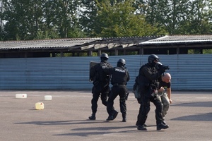 Zdjęcie czterech uczestników ćwiczeń - w tym trzech w hełmach i z bronią