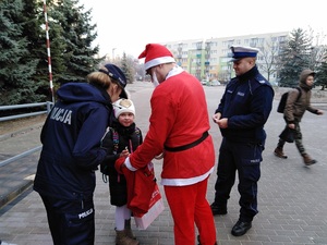 Policjanci z dzieckiem, obok mężczyzna przebrany za świętego Mikołaja.