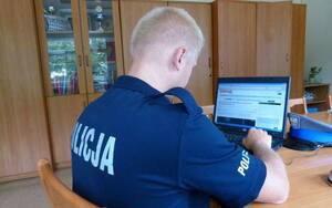 Policjant siedzi przy komputerze.