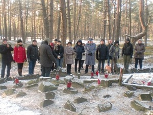 Zdjęcie przedstawicieli strony ukraińskiej i polskiej stojących na tle terenu leśnego przed zbiorowym miejscem pamięci
